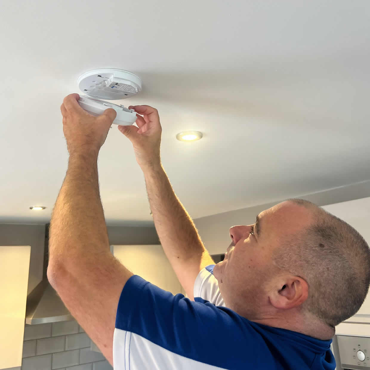 Smoke alarm installer fitting a detector in a Chesterfield property